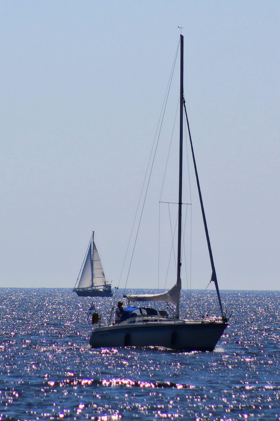 Due barche a vela navigano su acque blu aperte sotto cieli sereni.